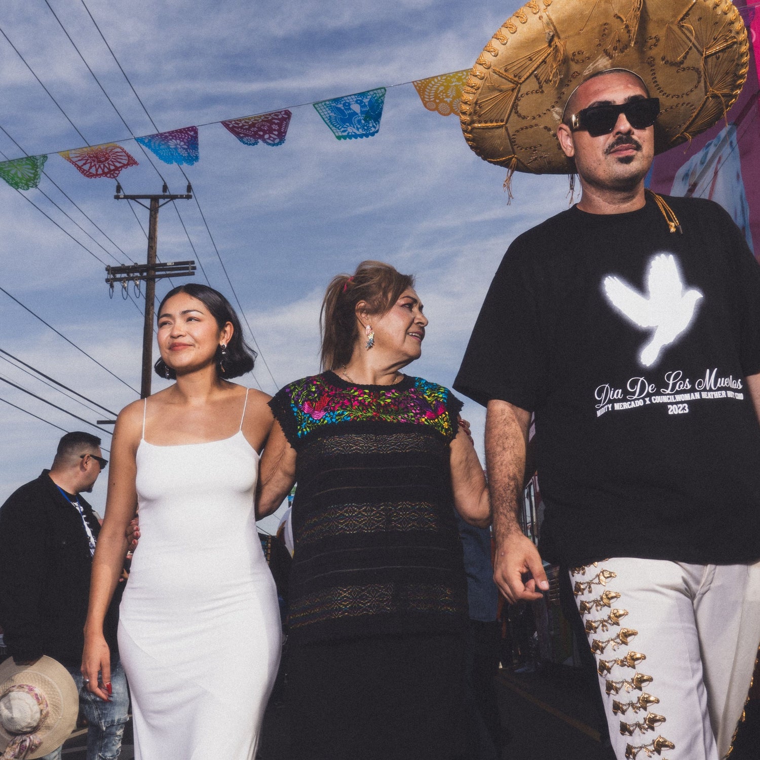 People walking on a street with colorful decorations and a blue sky.
